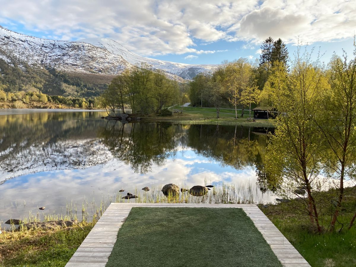 Utslag ved vannet i Vasset diskgolfpark — snødekte fjell og speilblankt vatn